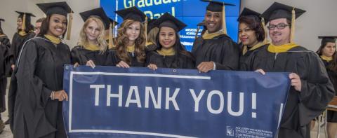 Graduates holding a sign reading "Thank you"