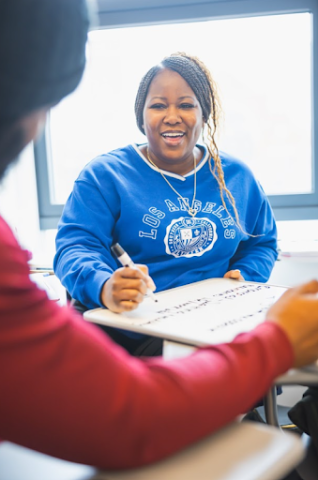 female presenting student writing on white board