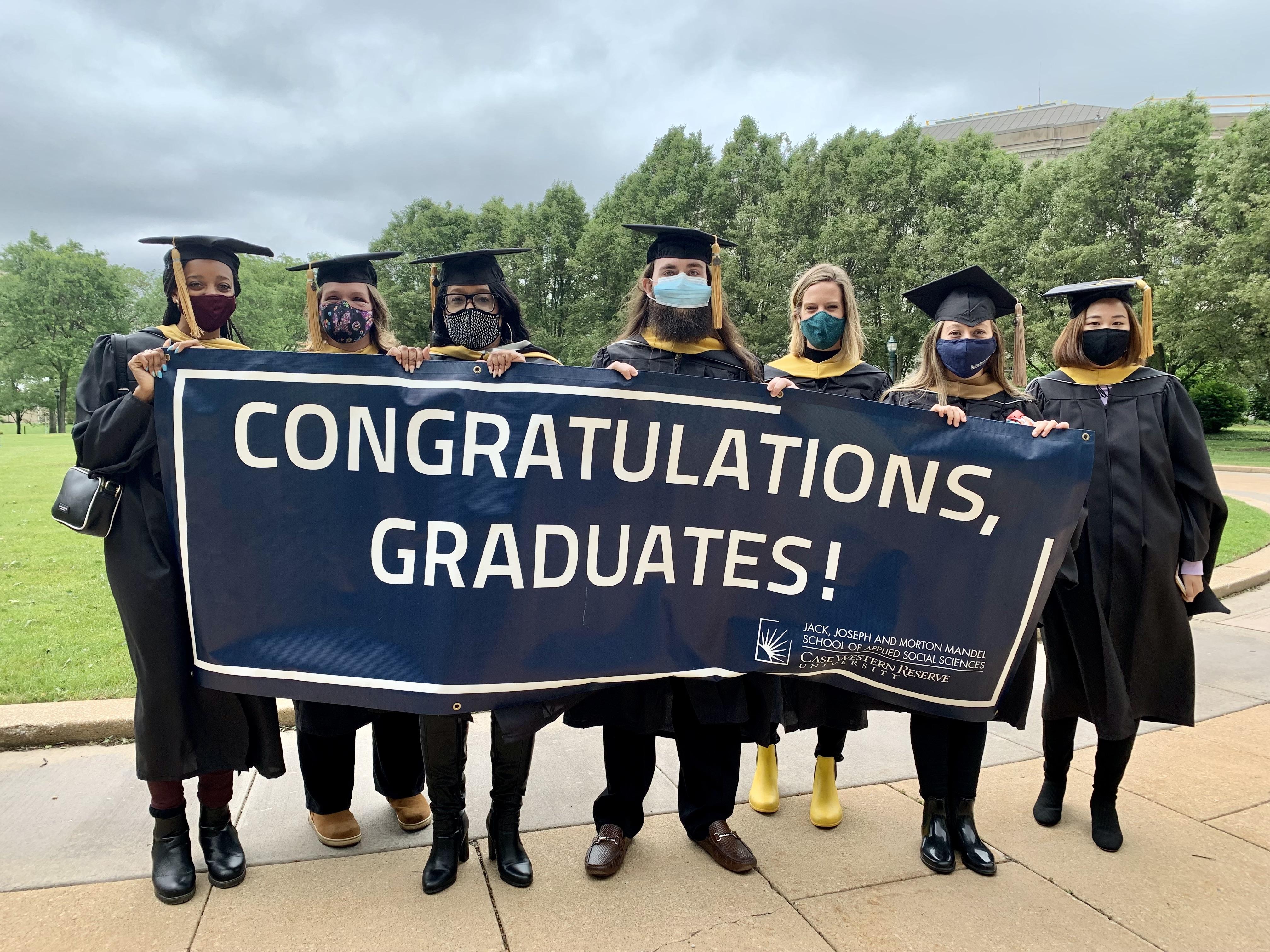 Graduates holding a banner that says, "Congratulations, Graduates!"