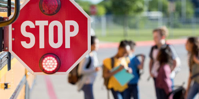 School bus stop sign in focus, group of children standing behind