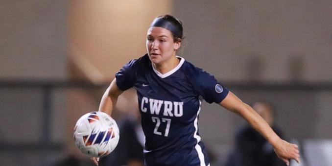 Samantha Cramin kicking a soccer ball in a CWRU uniform