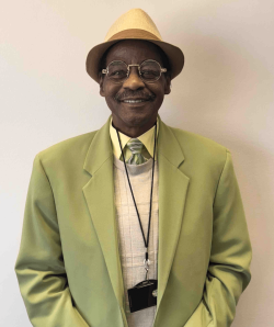 Russell Bell in a green jacket standing in front of a white wall
