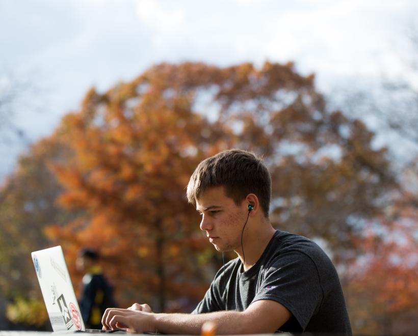 Student sitting outside on computer