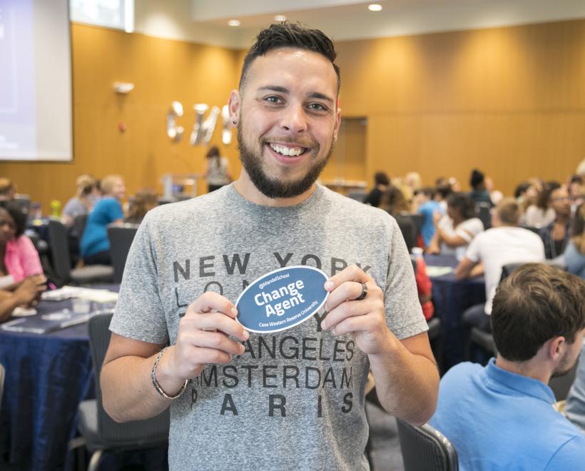 Young man holding change agent sticker smiling at camera