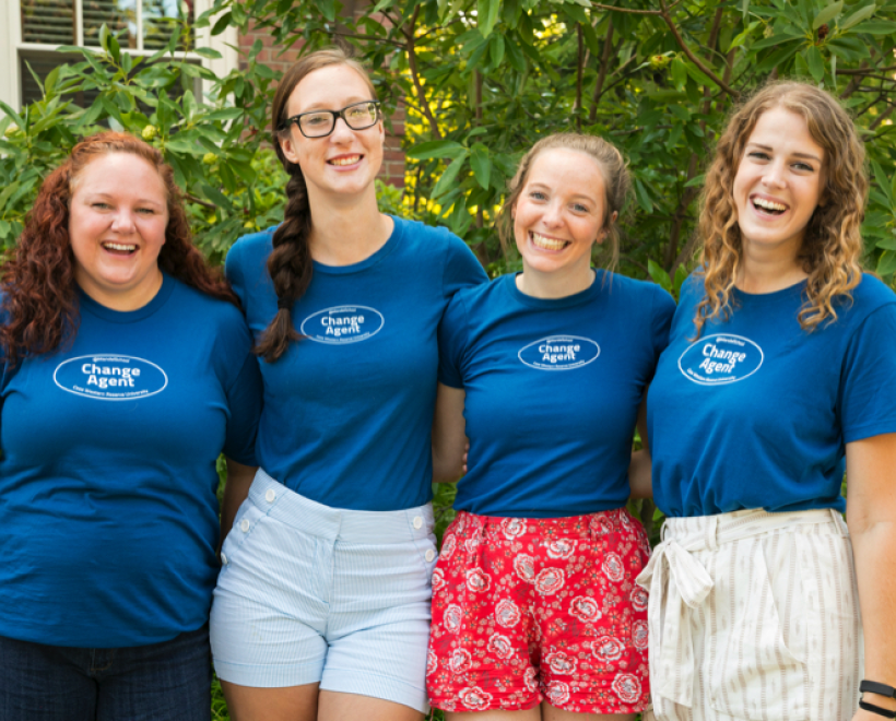 4 women wearing change agent shirts standing with arms around each other