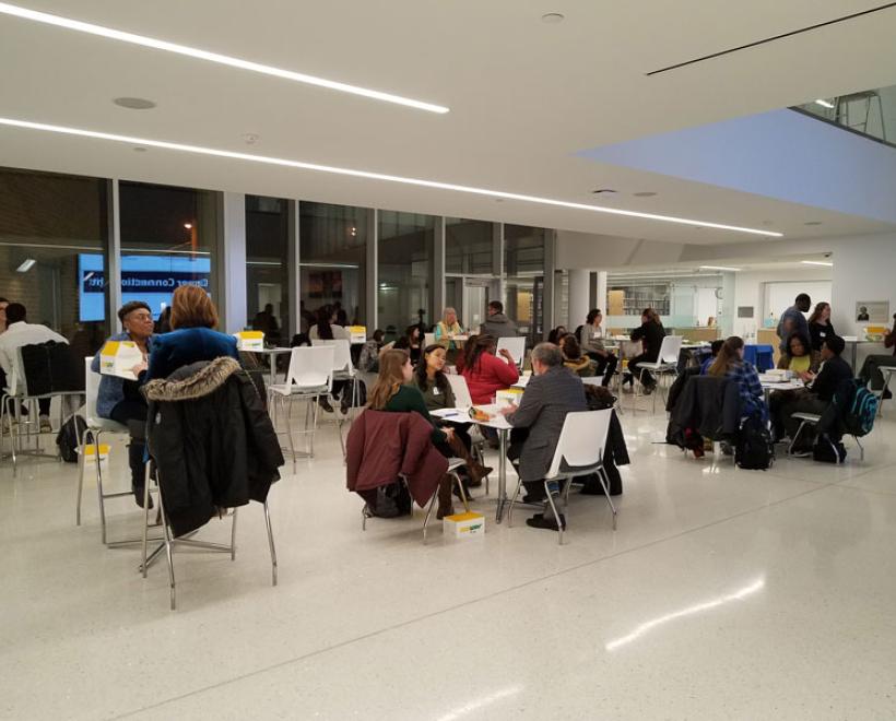 People sit at tables in Noble Commons and talk at night