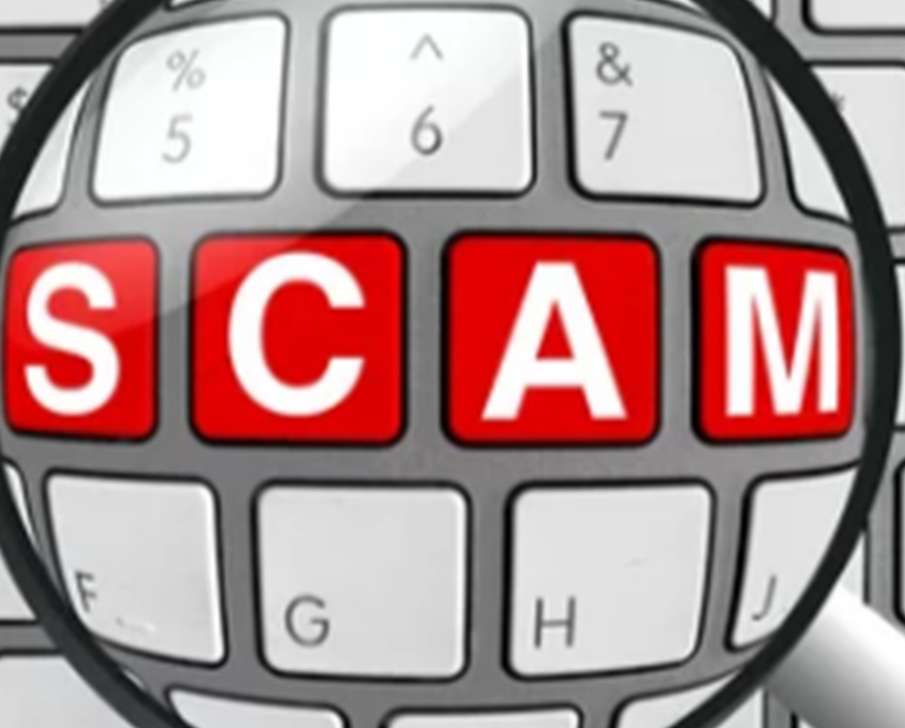 Magnifying glass over a keyboard with the words SCAM in red