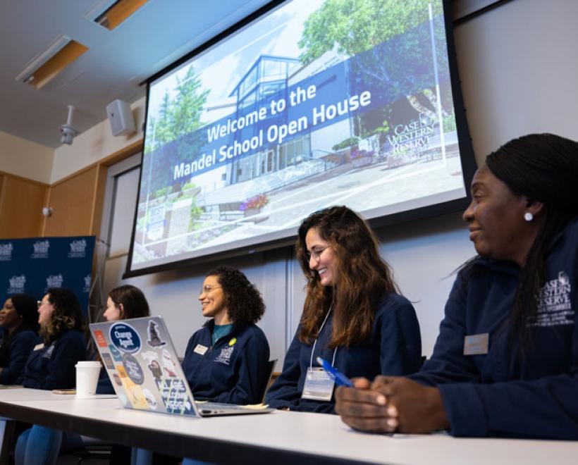 Several students sit at a table for a panel
