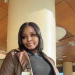 Damilola Ayetan stands with her hands in her coat pockets and smiles
