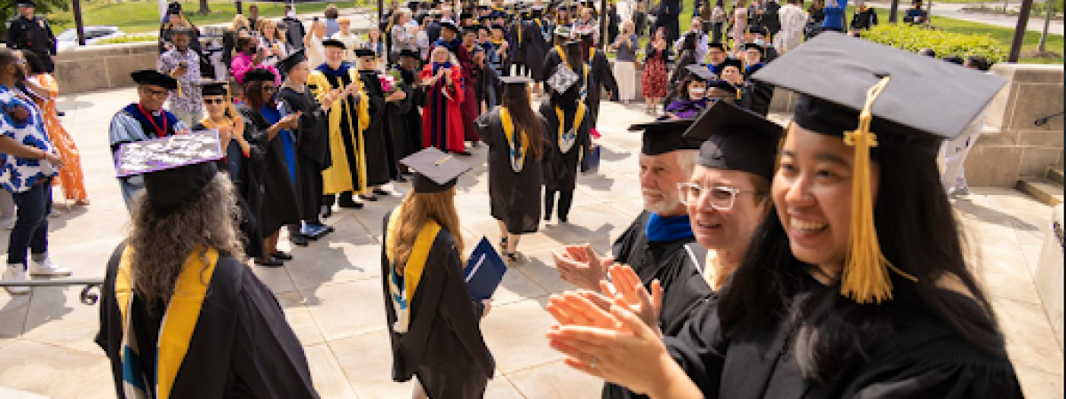 Graduate students clapping as other students pass by 