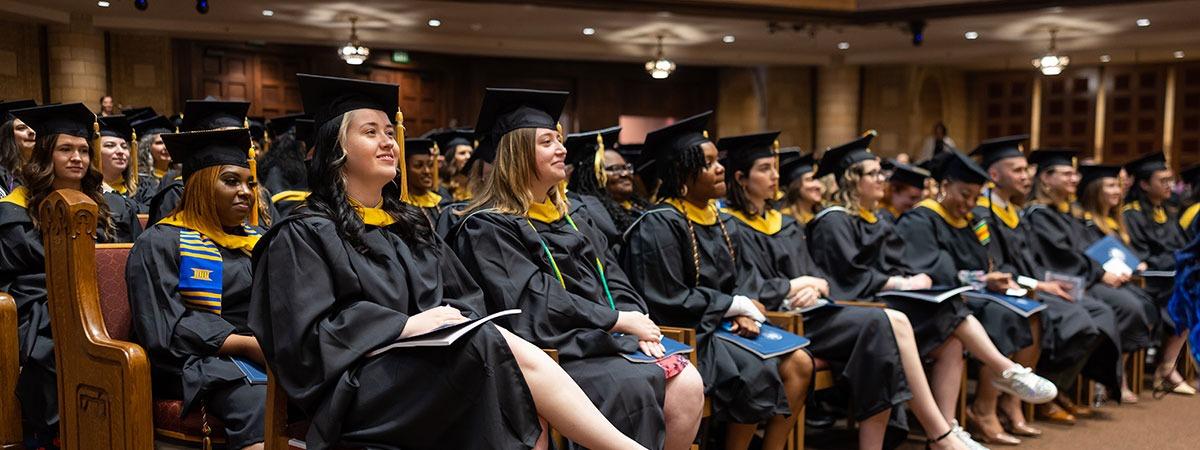 Graduates in caps and gowns sitting in seats 