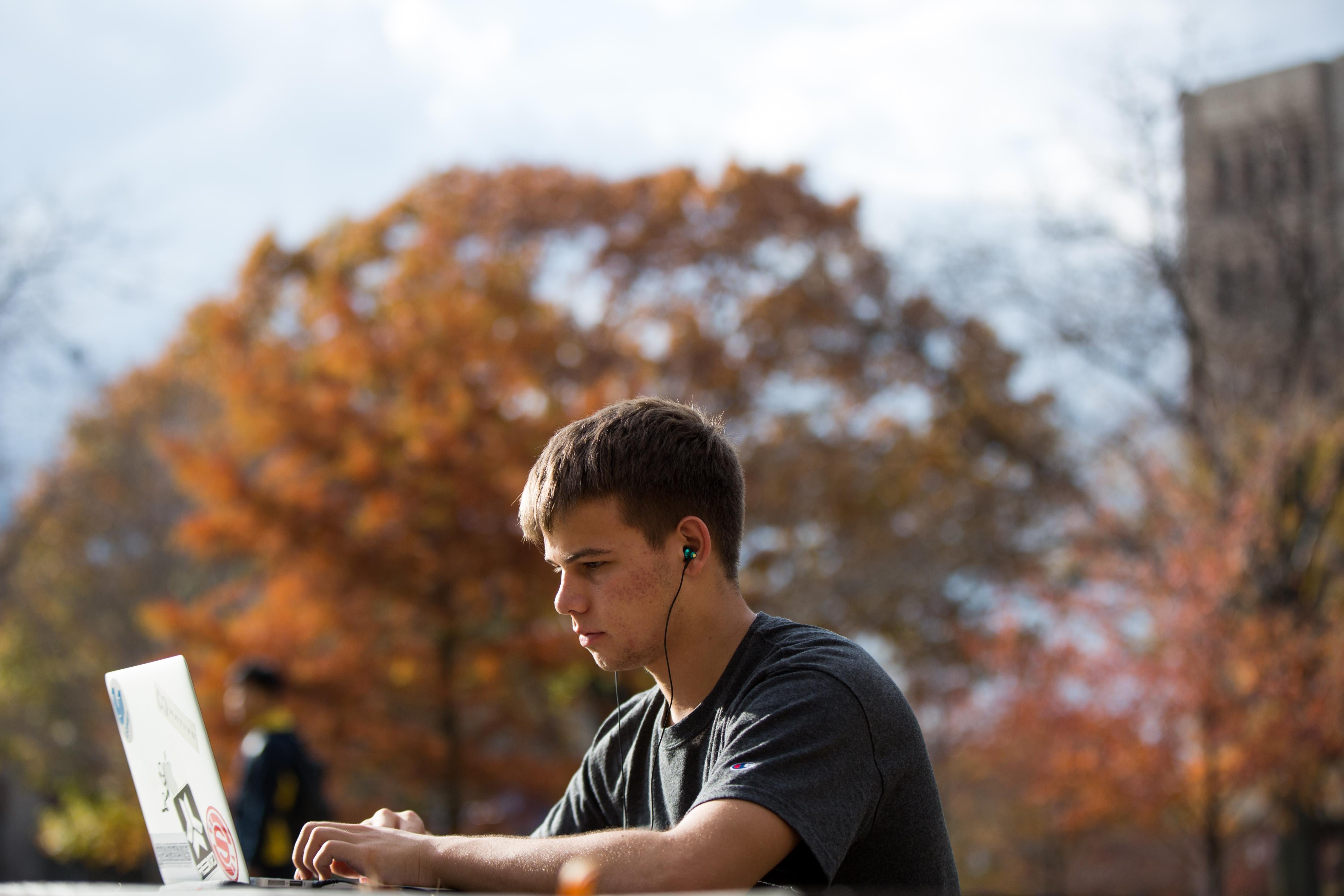 Student sitting outside on computer