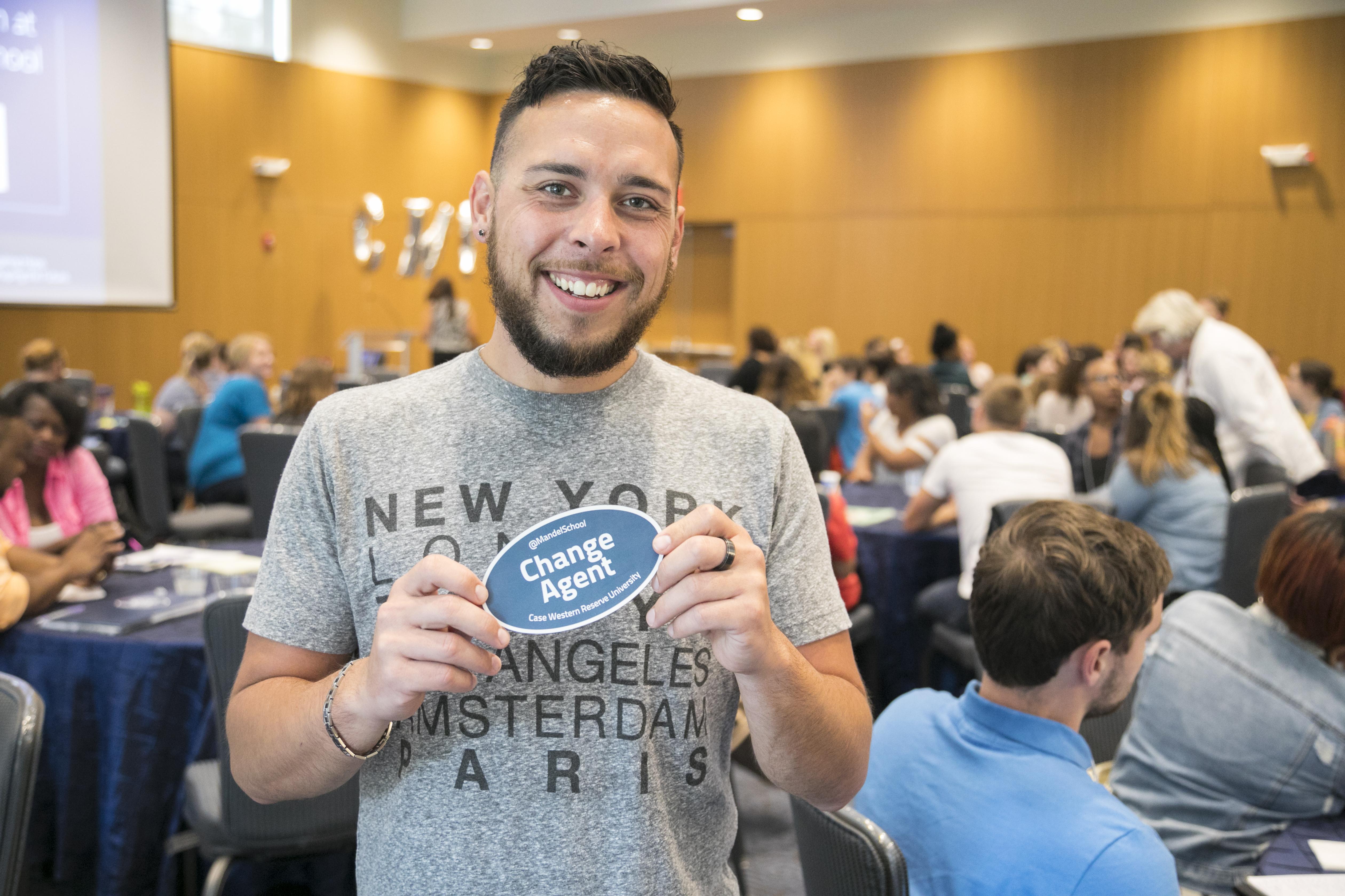 Young man holding change agent sticker smiling at camera