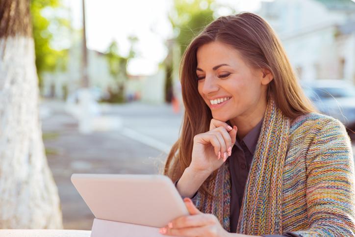 Girl smiling at her laptop with her hand on her chin