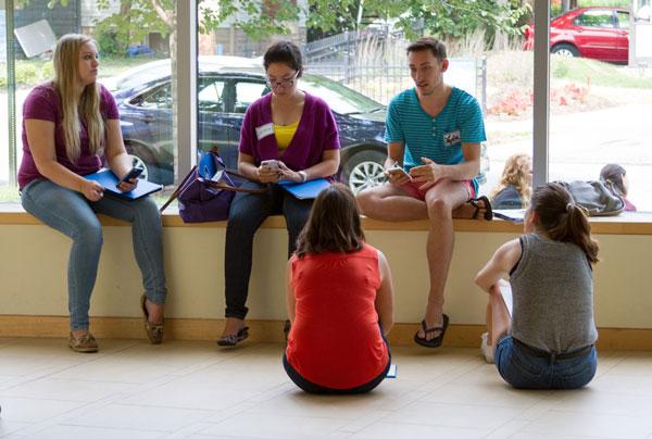 Five students sitting on a ledge and floor in the Mandel Center discussing