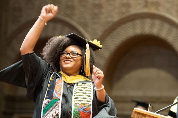 woman in graduation outfit with fist raised in the air