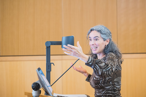 Female presenting instructor teaching in front of a computer