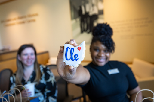 Female presenting student holding an Ohio state shaped cookie with Cle <3