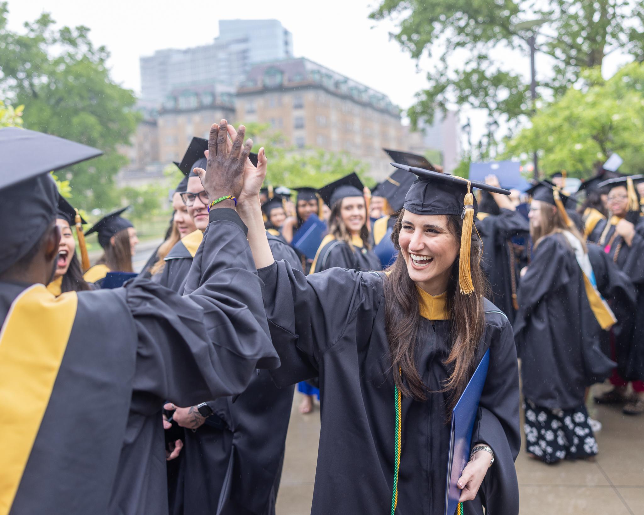 Graduates high five outside