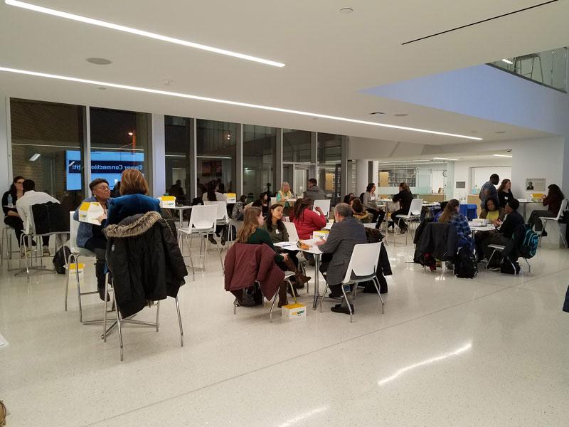 People sit at tables in Noble Commons and talk at night