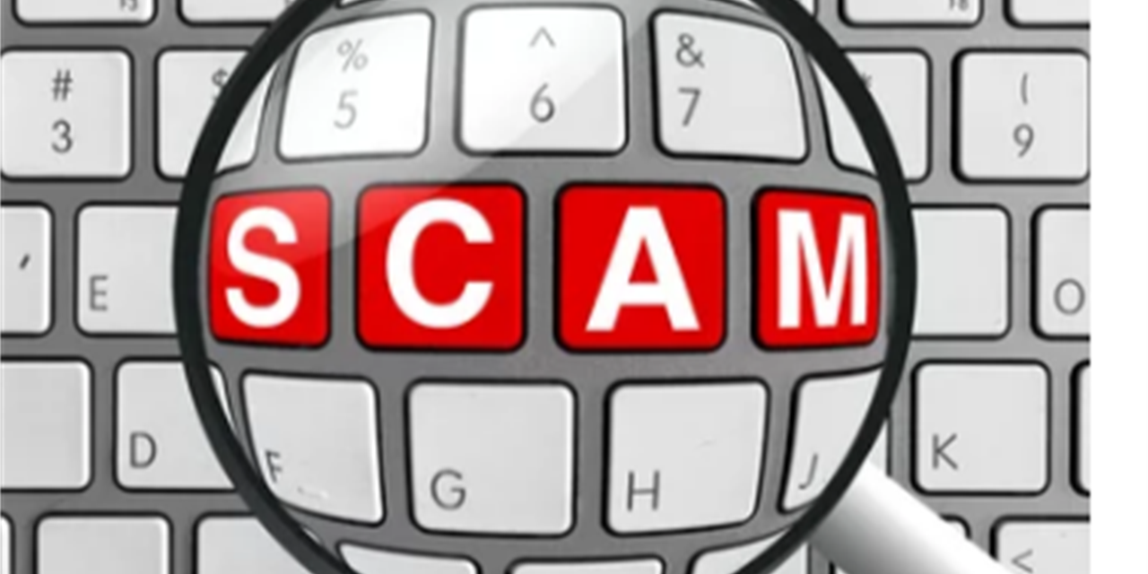 Magnifying glass over a keyboard with the words SCAM in red