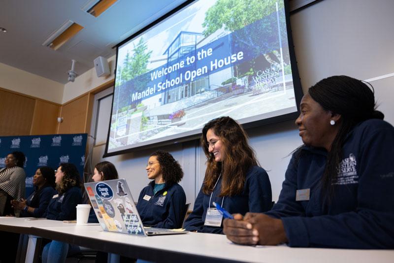 Several students sit at a table for a panel