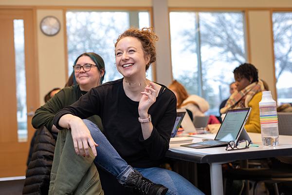 Two female smiling students in class