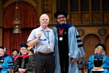 Dave Martin and Dexter Voisin smile on stage at commencement