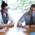 Faculty sitting and talking with three students at table
