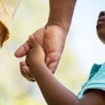 Black child holding an adult's hand