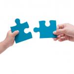 Two hands putting two puzzle pieces together
