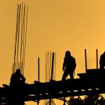 Construction workers on top of scaffolding at dusk