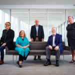 Five Mandel School researchers pose on or near a couch