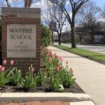 Mandel School brick sign in spring with tulips growing around it