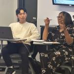 One student looks on as another talks to the class