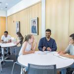 Two tables of students in Mandel Center talking