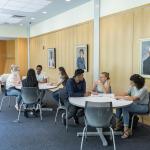 7 students sit at tables in Mandel Center and discuss things