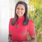 Lori Stokes smiles in front of some plants