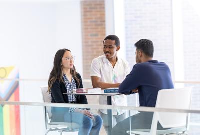 three students talking at a table
