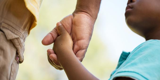 Black child holding an adult's hand