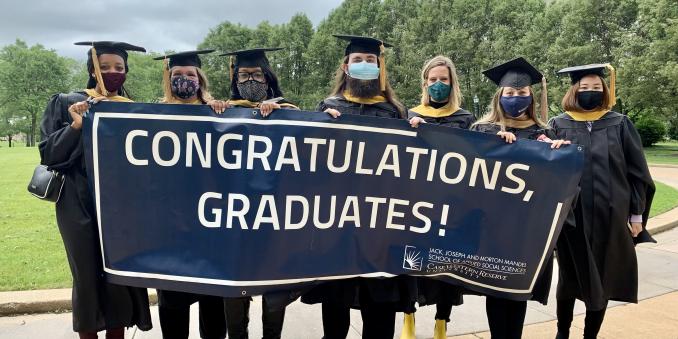 Graduates holding a banner that says, "Congratulations, Graduates!"