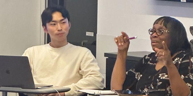 One student looks on as another talks to the class