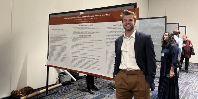Grayson Holt standing in front of a poster presentation