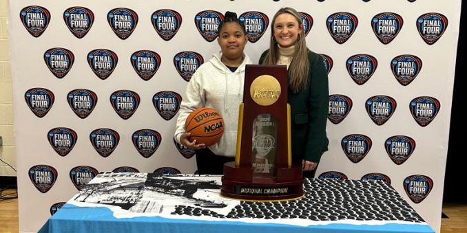 Taylor Amato with a student holding a basketball at a NCAA Final Four booth