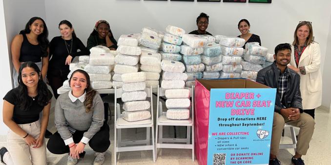 Students and staff stand next to the 2023 diaper donations