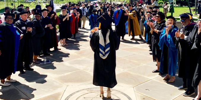 Grad walks out of the Maltz into the Mandel School clap-out celebration