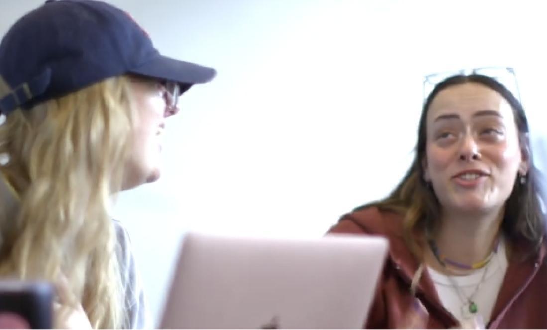 Two female students talking over a computer