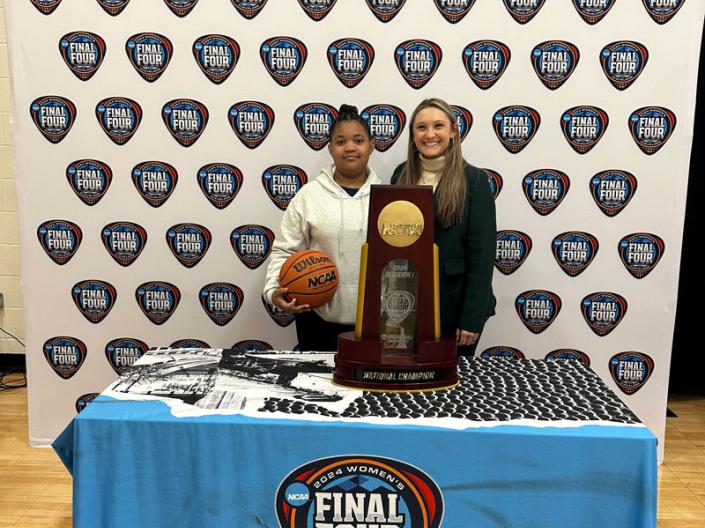 Taylor Amato with a student holding a basketball at a NCAA Final Four booth