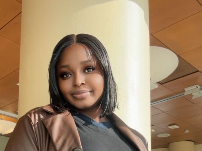 Damilola Ayetan stands with her hands in her coat pockets and smiles
