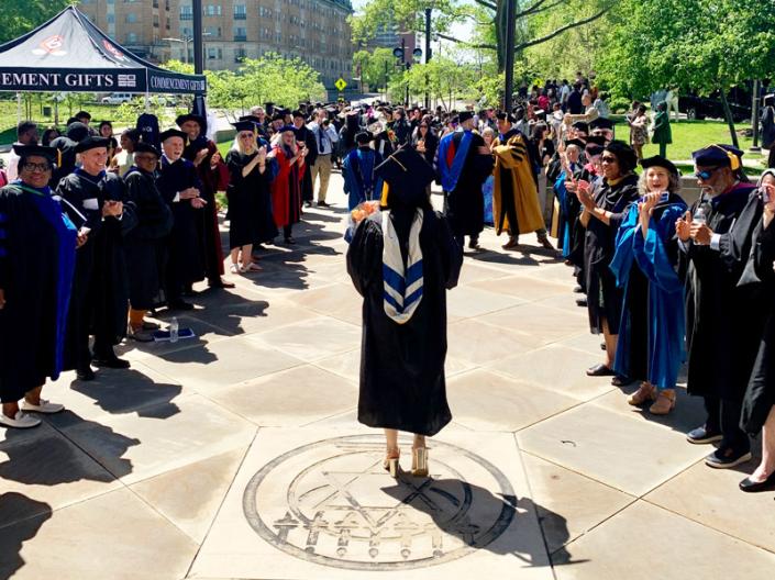 Grad walks out of the Maltz into the Mandel School clap-out celebration